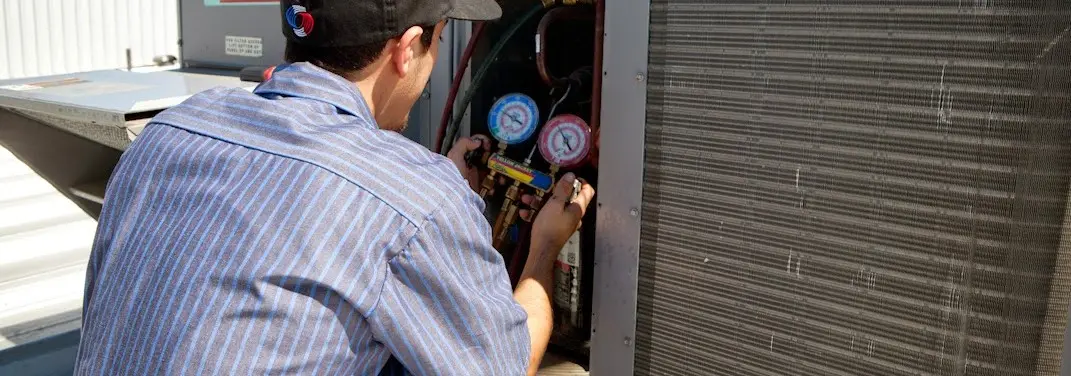 HVAC technician servicing a condenser unit in New Holland